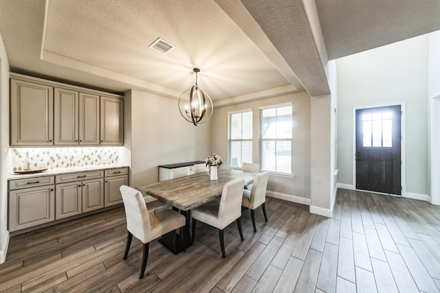 dining room featuring baseboards, a notable chandelier, a tray ceiling, and wood finished floors