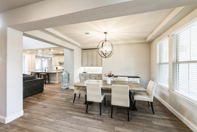 dining space featuring baseboards, wood finished floors, visible vents, and an inviting chandelier