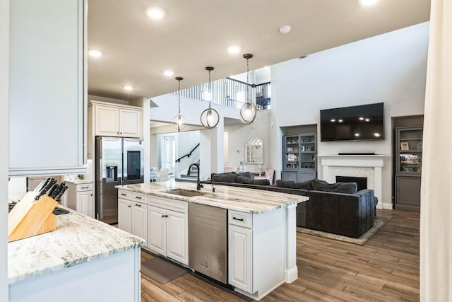 kitchen with a fireplace, appliances with stainless steel finishes, light wood-style floors, white cabinets, and a sink