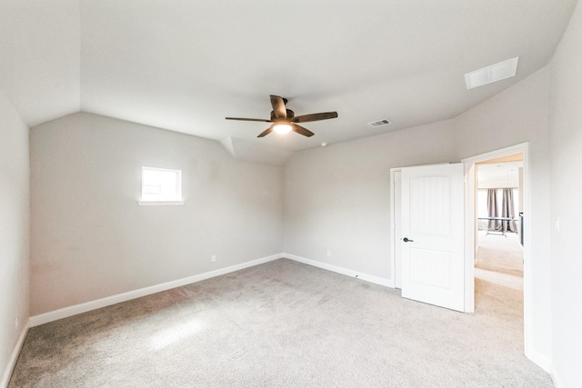 spare room with carpet floors, baseboards, visible vents, and vaulted ceiling