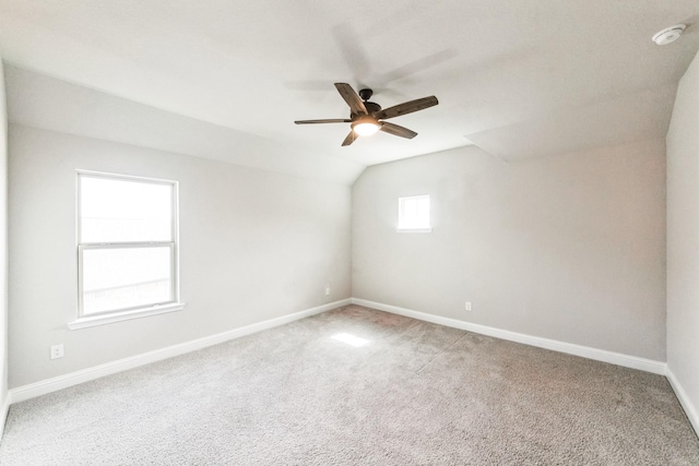 carpeted empty room with lofted ceiling, ceiling fan, and baseboards