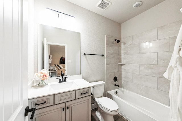 ensuite bathroom featuring visible vents, a textured wall, toilet, ensuite bath, and vanity