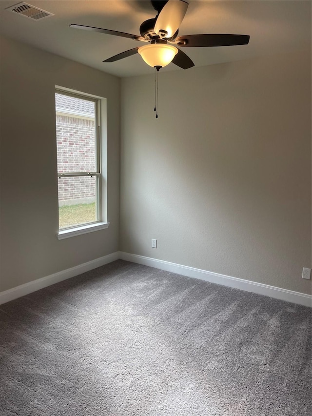 carpeted spare room featuring a ceiling fan, visible vents, and baseboards