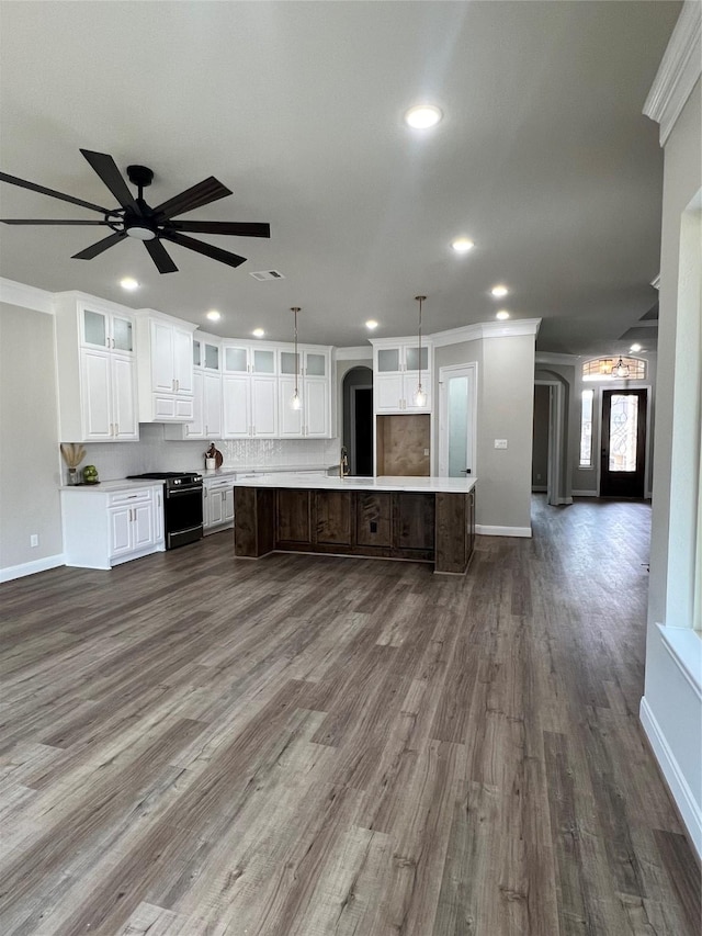 kitchen featuring light countertops, a large island, black range with gas stovetop, and glass insert cabinets