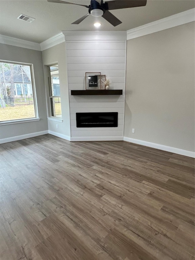 unfurnished living room featuring a large fireplace, ornamental molding, wood finished floors, and visible vents