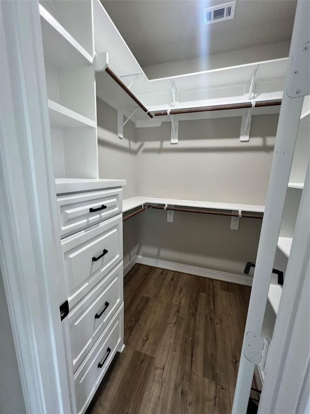 walk in closet featuring dark wood-style flooring, visible vents, and built in study area