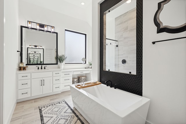 full bath featuring a stall shower, a freestanding tub, and vanity