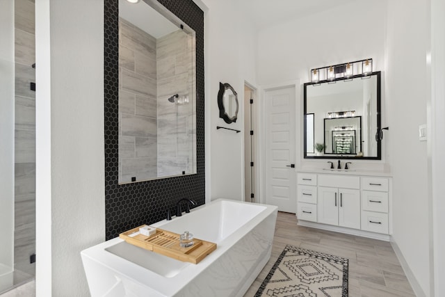 bathroom with a freestanding bath, a shower stall, vanity, and baseboards