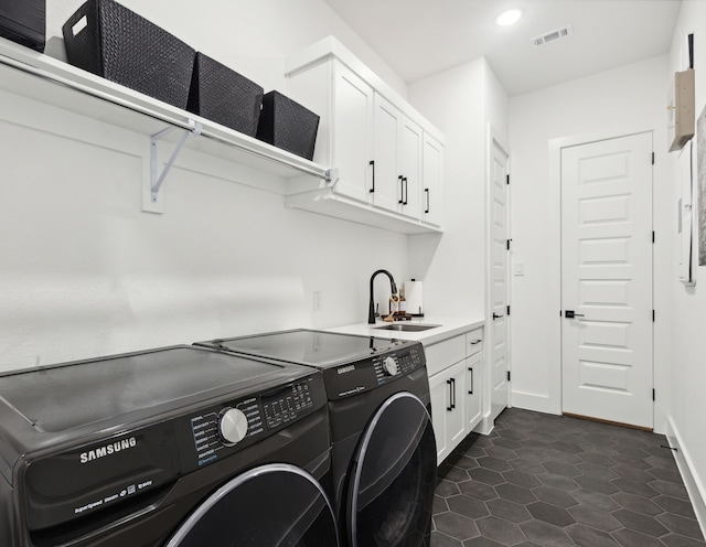 laundry area with visible vents, cabinet space, washing machine and dryer, a sink, and baseboards