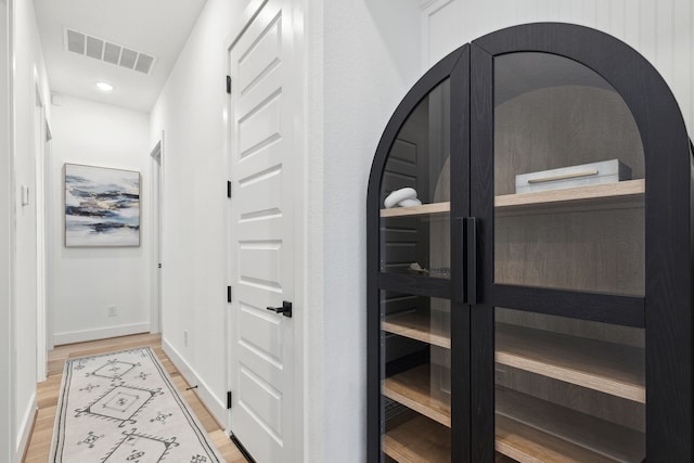 hall featuring baseboards, visible vents, wood finished floors, and recessed lighting