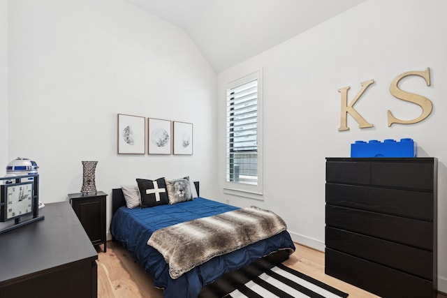 bedroom featuring lofted ceiling, light wood-style flooring, and baseboards