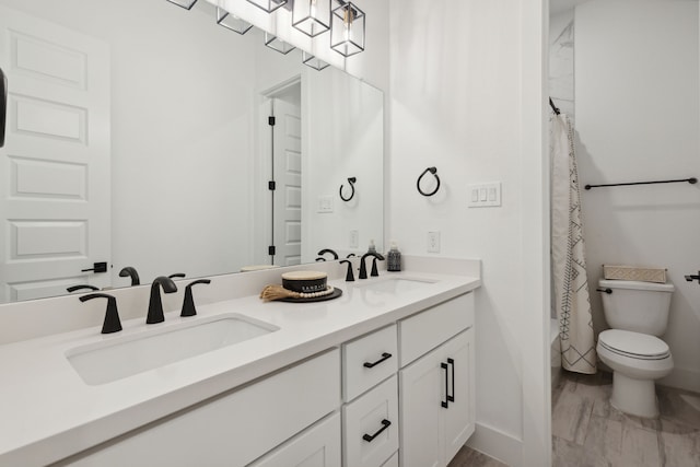 bathroom with marble finish floor, double vanity, a sink, and toilet