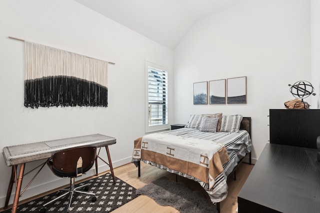 bedroom featuring lofted ceiling, wood finished floors, and baseboards