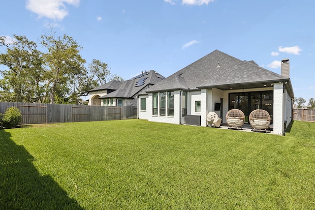 rear view of house featuring a fenced backyard, a yard, a chimney, and a patio