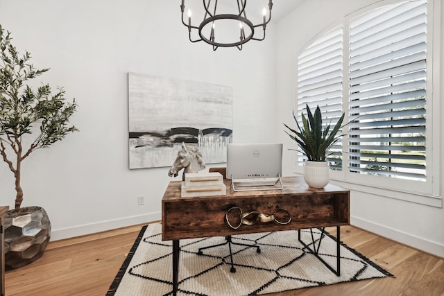 office area with baseboards, a notable chandelier, and light wood finished floors