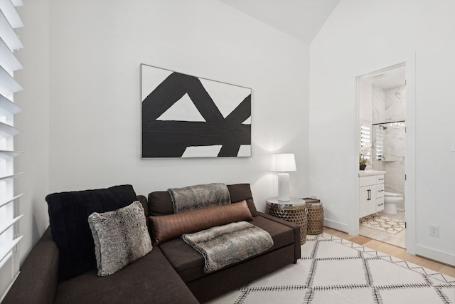 living area featuring vaulted ceiling, light wood finished floors, and baseboards