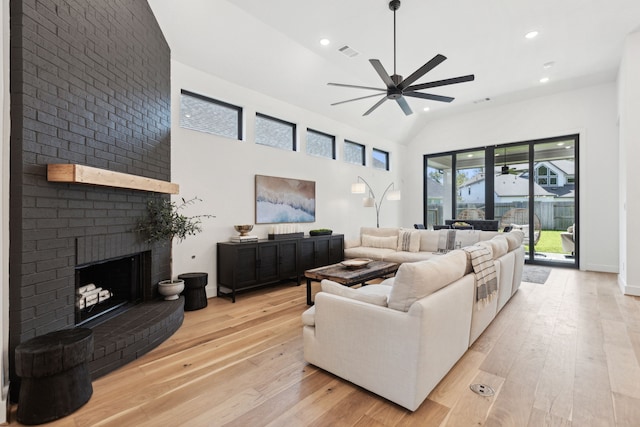 living area with ceiling fan, a fireplace, visible vents, and light wood-style floors