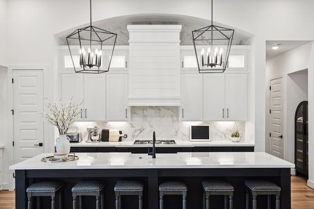 kitchen featuring a breakfast bar, an island with sink, and white cabinetry