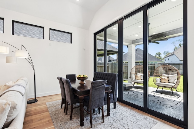 dining space featuring lofted ceiling, plenty of natural light, baseboards, and wood finished floors