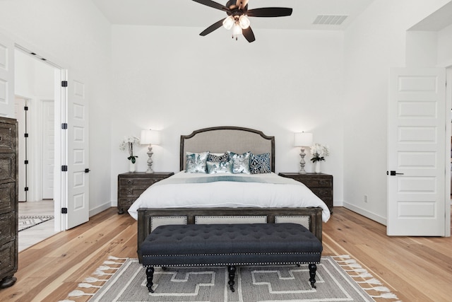 bedroom featuring visible vents, ceiling fan, baseboards, and wood finished floors