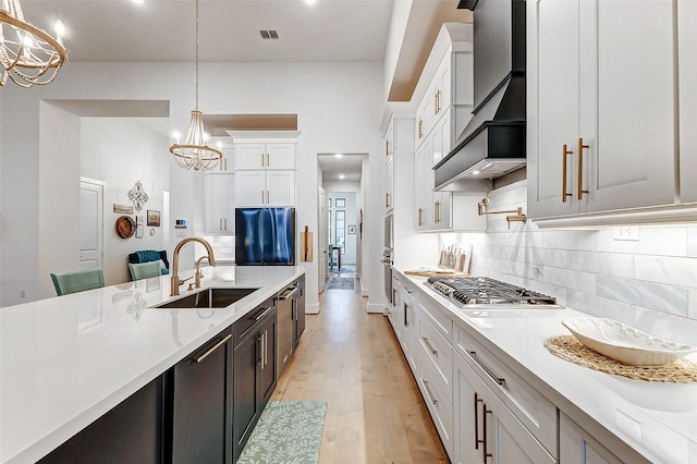 kitchen featuring light countertops, a sink, white cabinetry, and decorative light fixtures