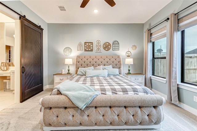 bedroom with a barn door, light carpet, a ceiling fan, visible vents, and baseboards