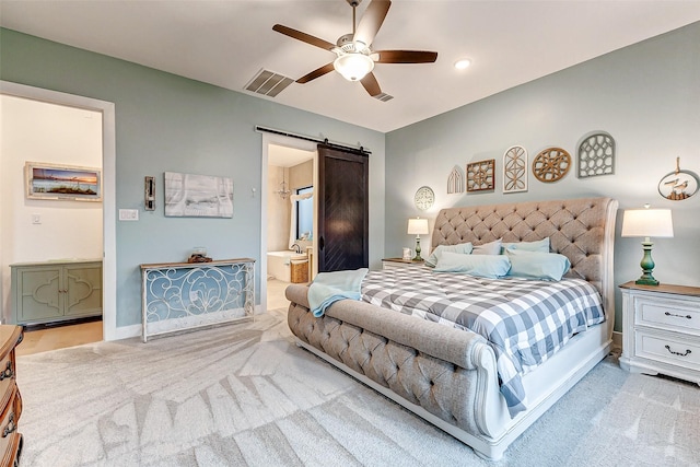 bedroom featuring a barn door, connected bathroom, light colored carpet, visible vents, and baseboards