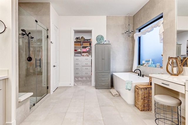 bathroom featuring a soaking tub, tile patterned flooring, a walk in closet, vanity, and a shower stall