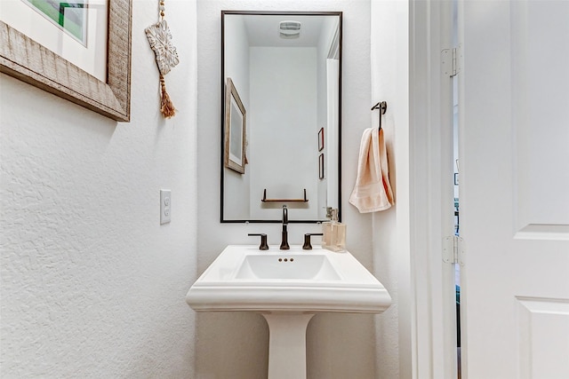 bathroom featuring a textured wall, a sink, and visible vents