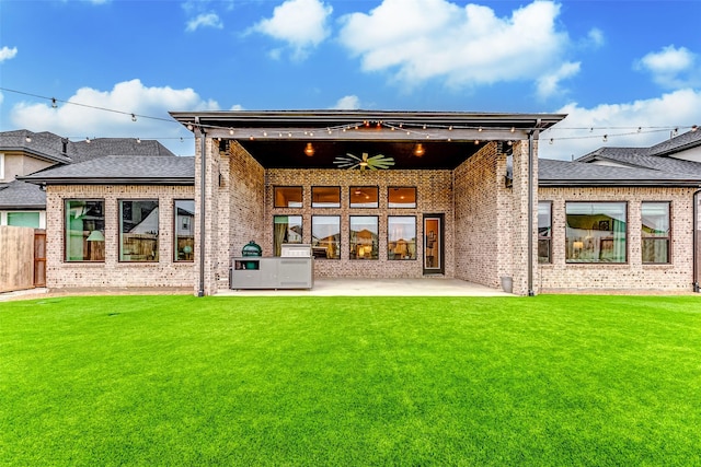 rear view of house featuring ceiling fan, fence, a yard, a patio area, and brick siding