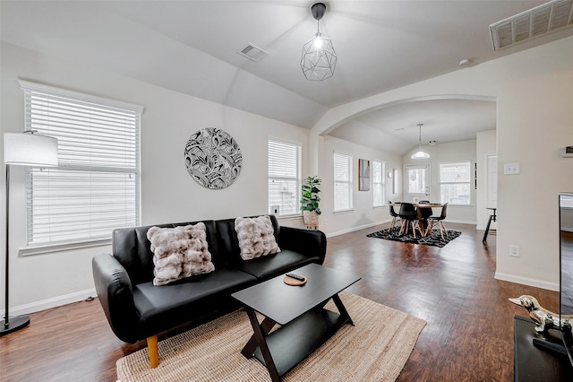 living area with baseboards, visible vents, arched walkways, and wood finished floors