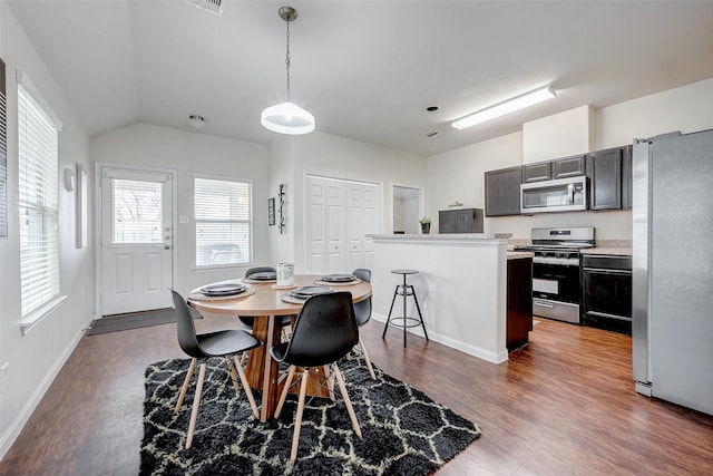 dining space featuring dark wood-type flooring, lofted ceiling, visible vents, and baseboards