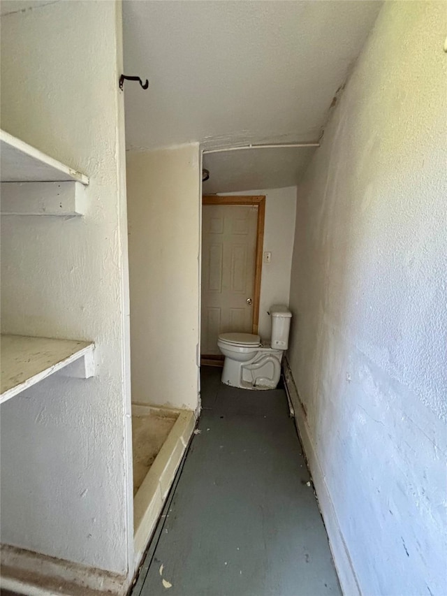 bathroom featuring a textured wall and toilet