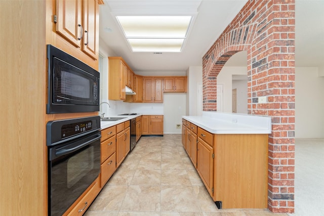 kitchen featuring black appliances, under cabinet range hood, light countertops, and a sink