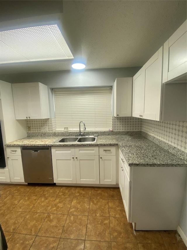 kitchen featuring dishwasher, tasteful backsplash, a sink, and white cabinetry