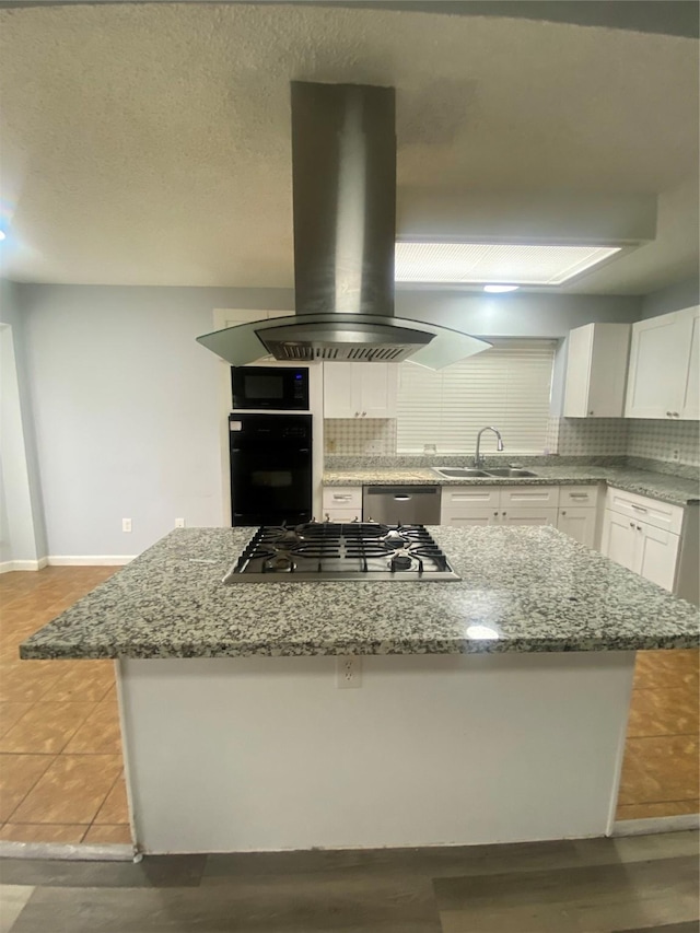 kitchen with island exhaust hood, backsplash, white cabinetry, a sink, and black appliances