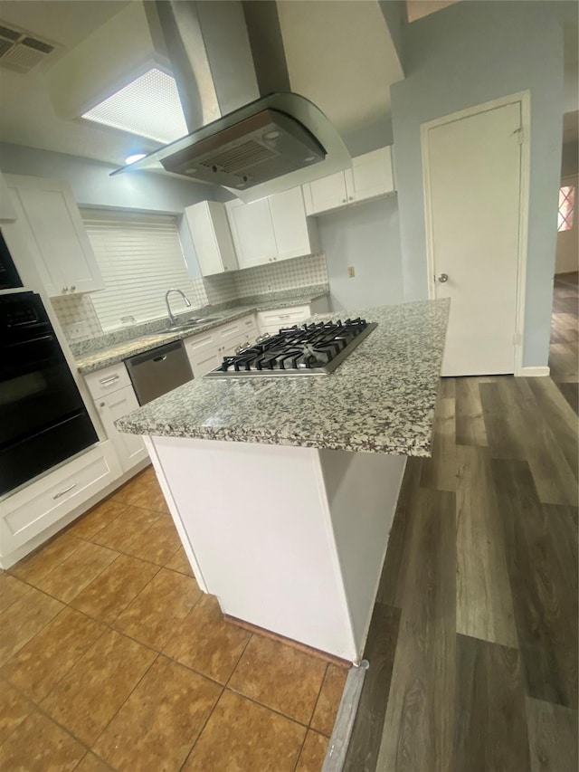 kitchen featuring island range hood, visible vents, white cabinetry, appliances with stainless steel finishes, and decorative backsplash