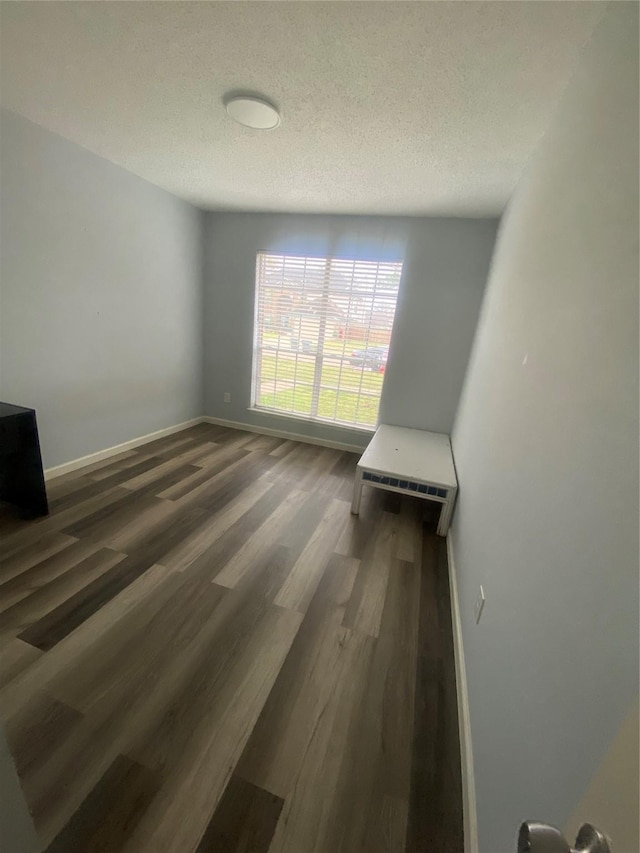 bedroom featuring a textured ceiling, baseboards, and dark wood-style flooring