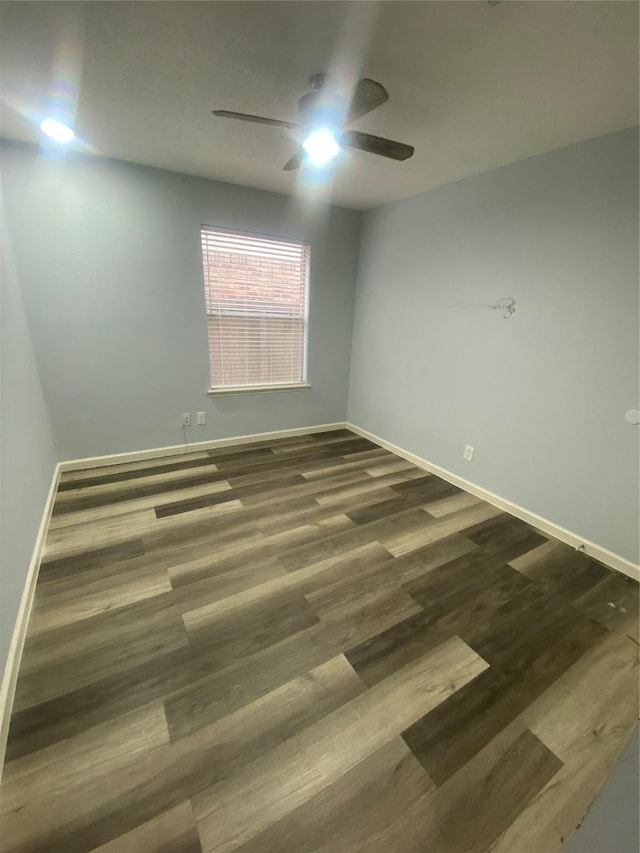 spare room with ceiling fan, baseboards, and dark wood-style flooring