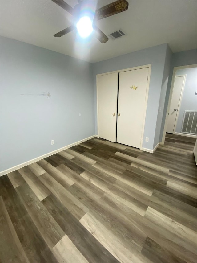 unfurnished bedroom featuring ceiling fan, dark wood finished floors, visible vents, and baseboards