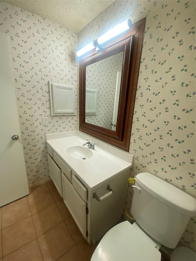 half bath with wallpapered walls, toilet, tile patterned floors, a textured ceiling, and vanity