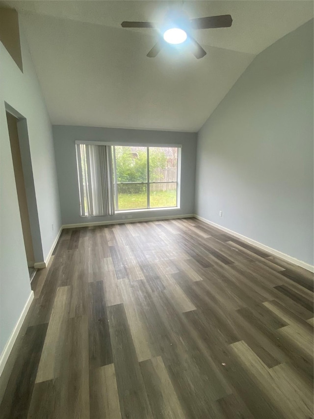 empty room featuring vaulted ceiling, dark wood-style floors, a ceiling fan, and baseboards