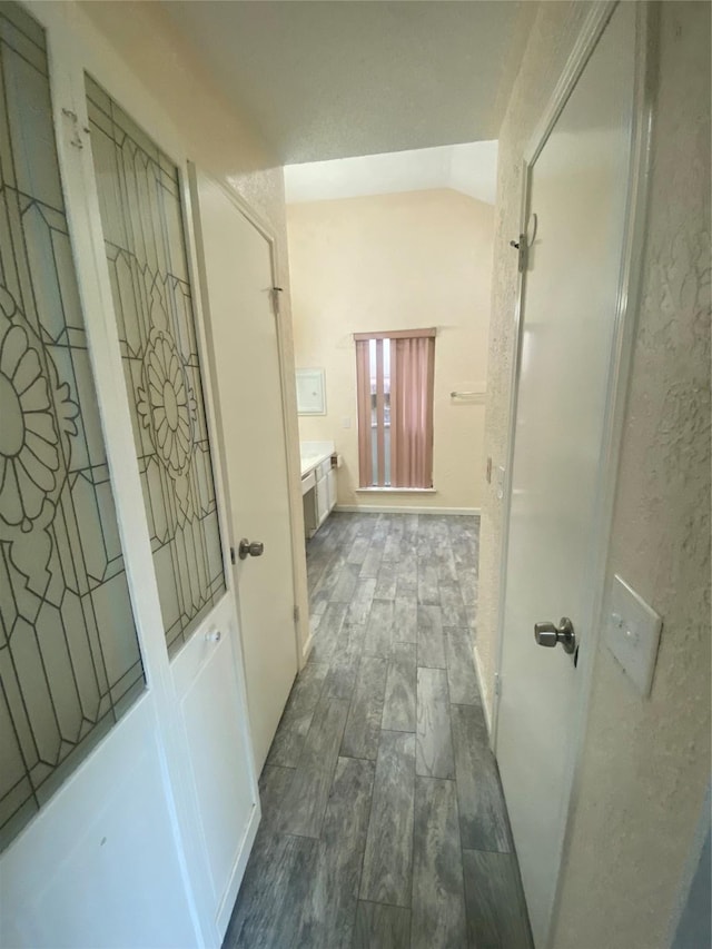 corridor featuring vaulted ceiling and wood finish floors