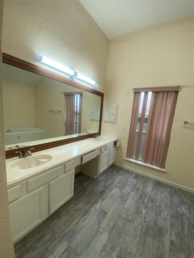 bathroom with double vanity, a textured wall, a sink, and wood finished floors