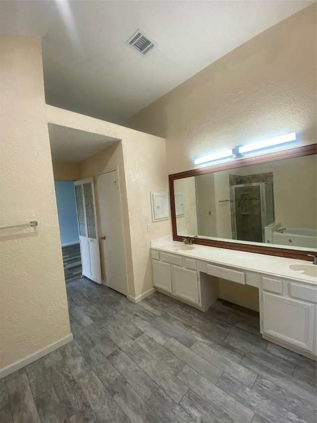 full bath with a textured wall, visible vents, wood finished floors, and vanity