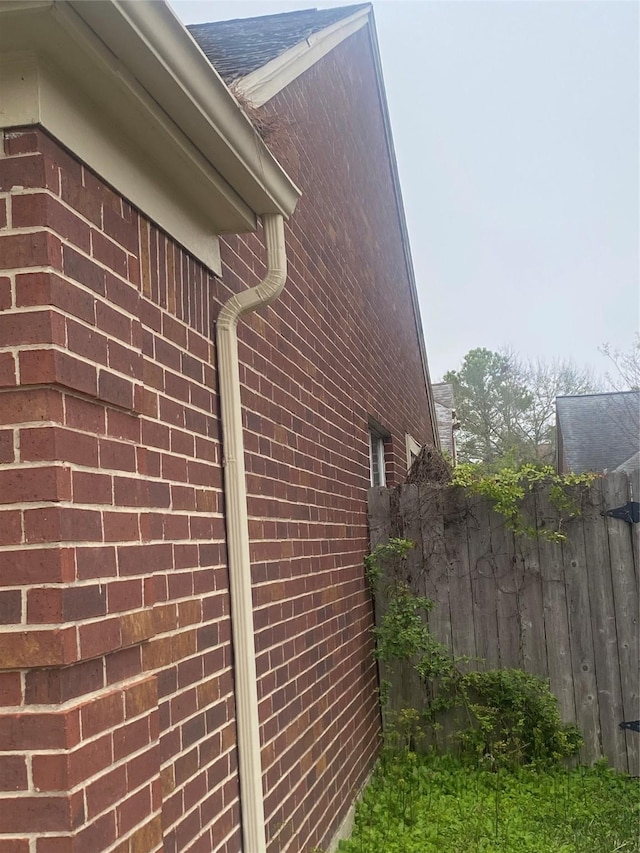 view of property exterior featuring fence and brick siding