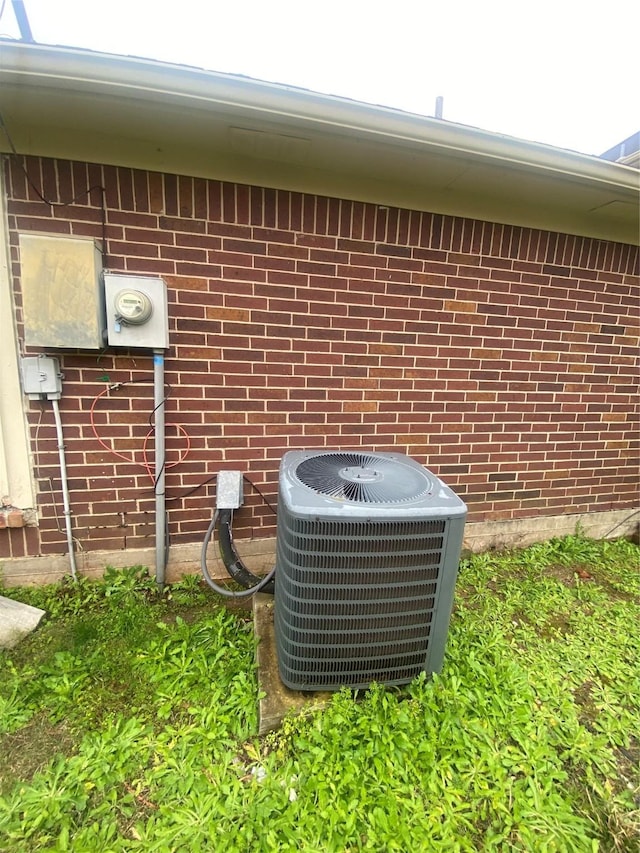 exterior details featuring electric meter, central AC, and brick siding