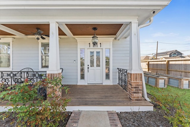 property entrance featuring covered porch, ceiling fan, and fence