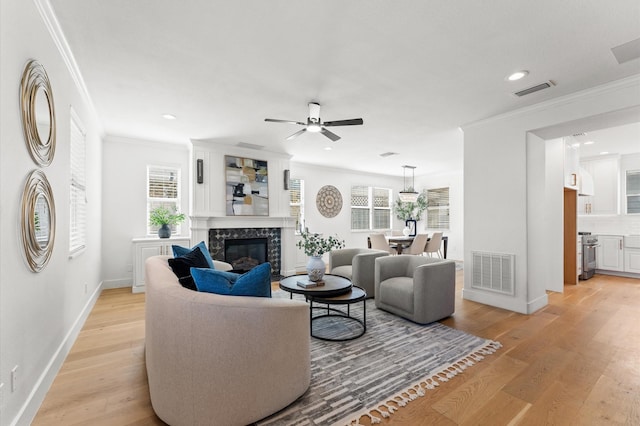 living area with light wood-style flooring, visible vents, and a high end fireplace