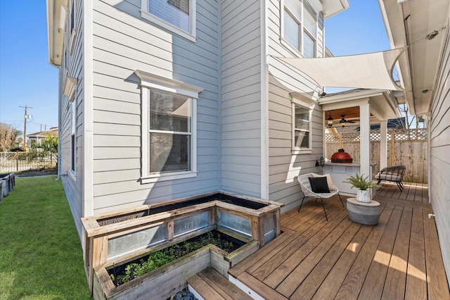 wooden deck with fence, a ceiling fan, and a yard